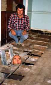 Lord Saye (peeking through hole) examining floorboards under repair.